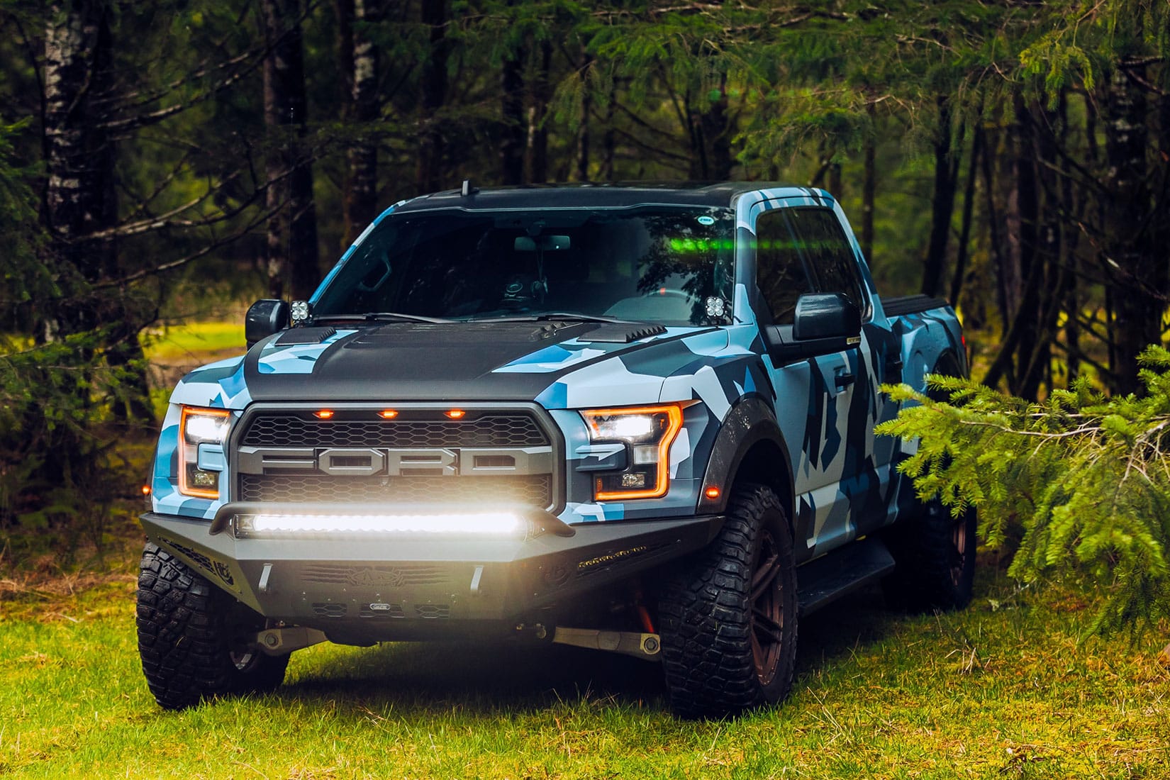 Front view of a blue camo Ford truck with LED light bar mounted below its grille and headlights.