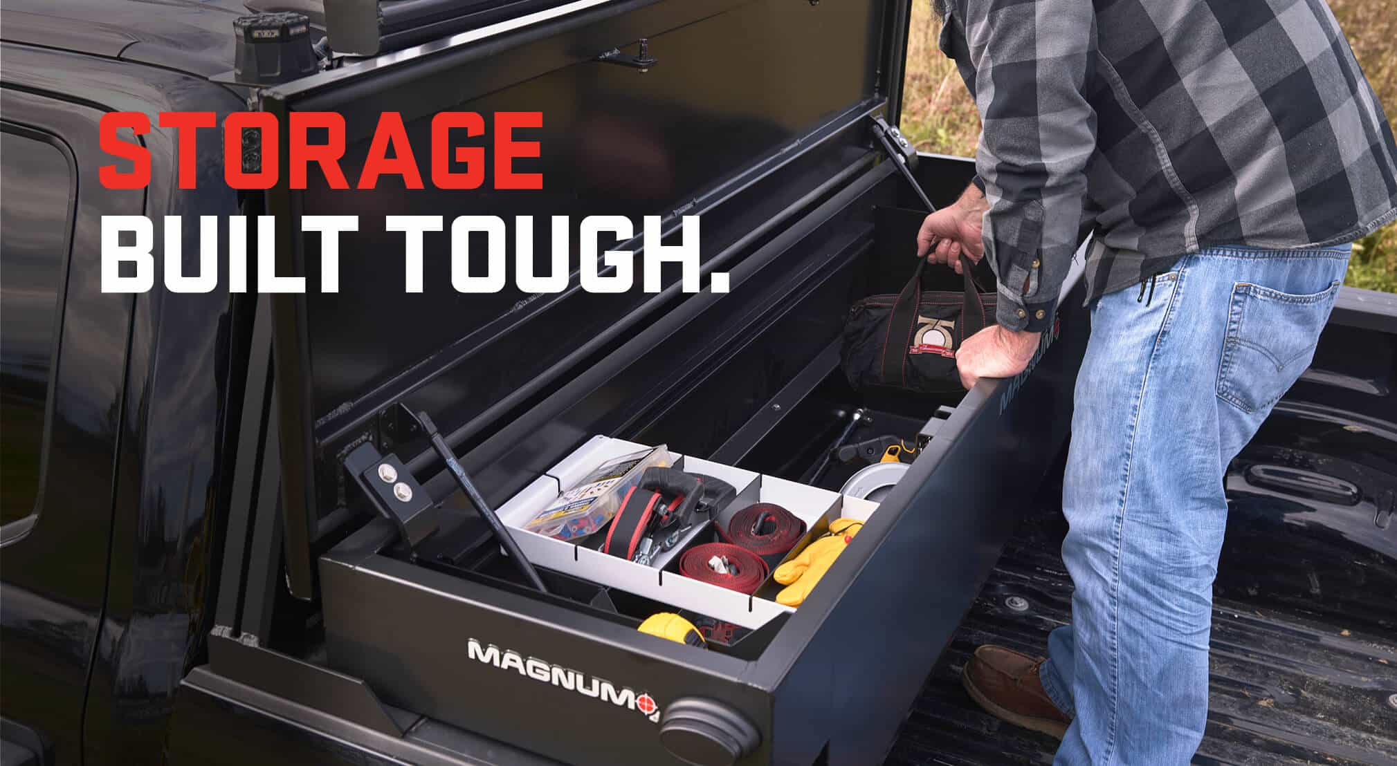 black pickup truck showing an open truckbed toolbox with a person reaching in for a bag of tools and the caption reads storage built tough